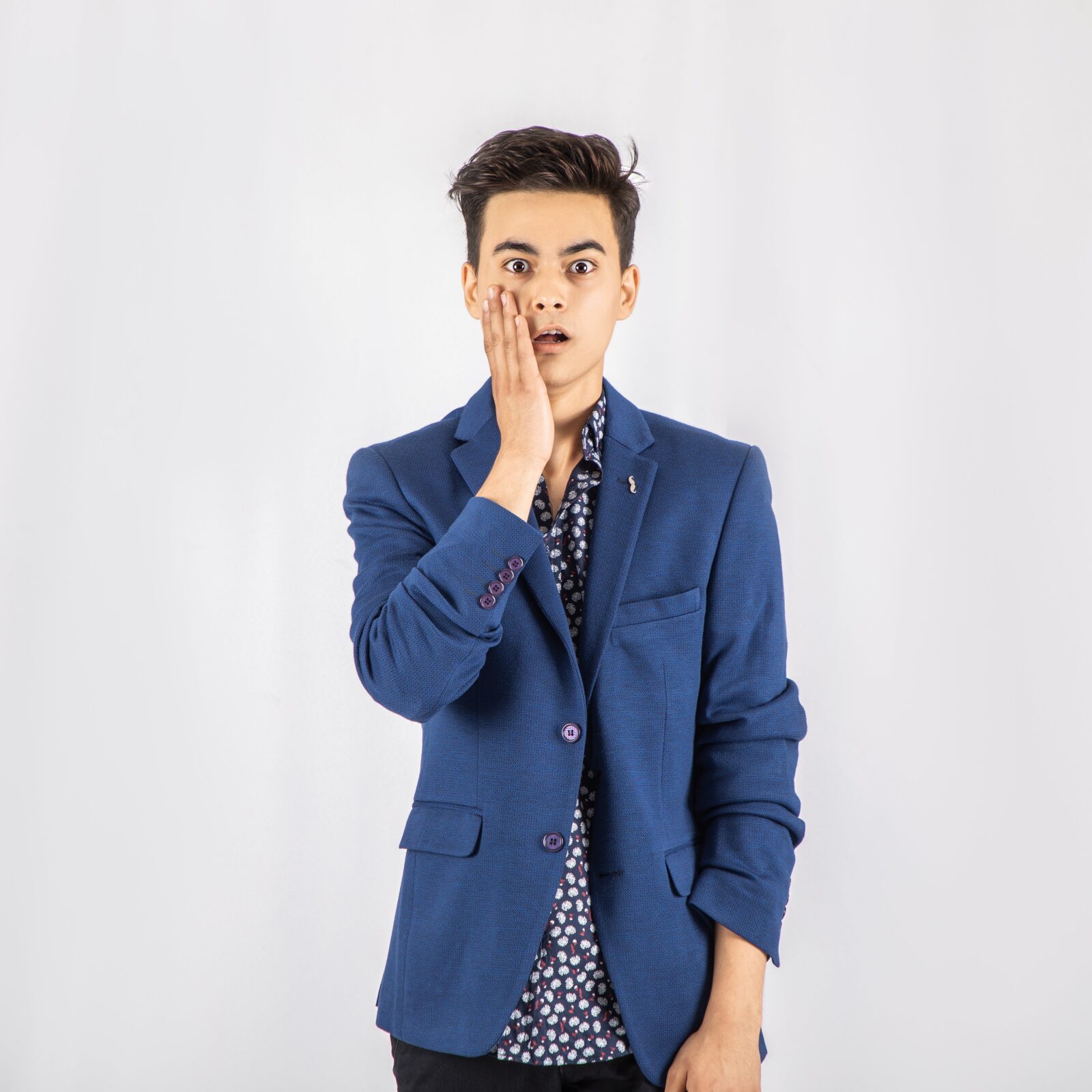 Photo of Shocked Man in Blue Blazer Standing In Front of White Background