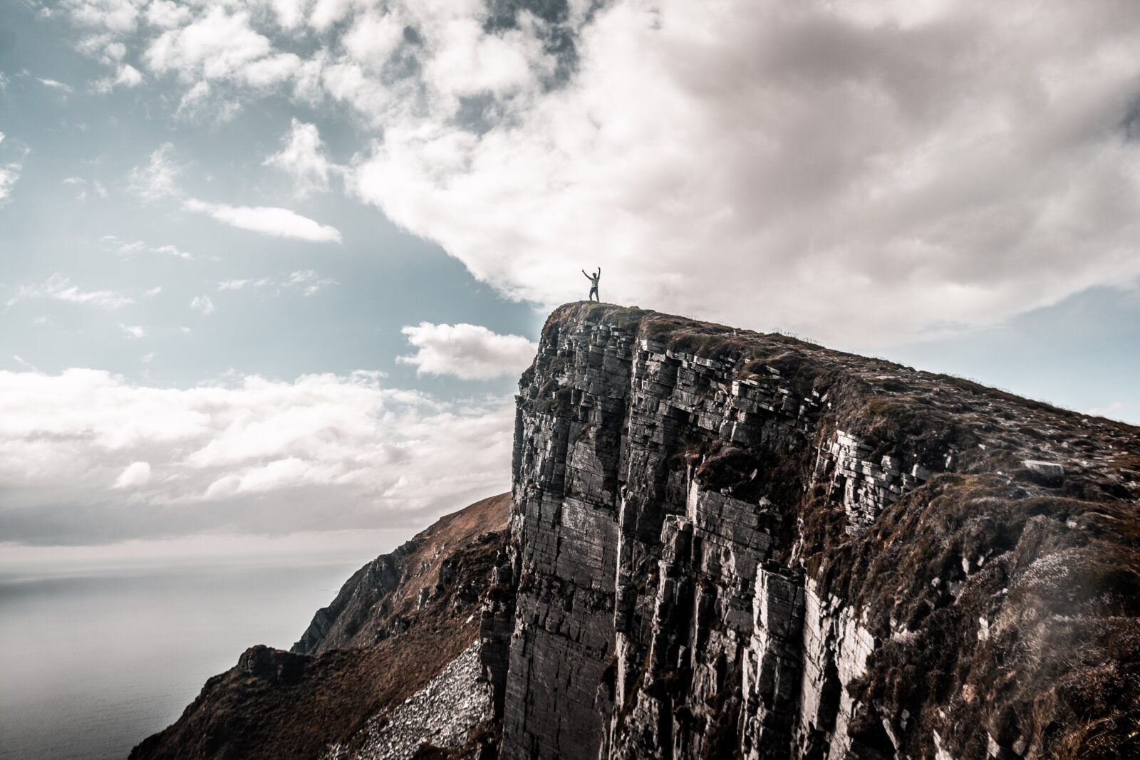 Scenic Photo of Man Standing on Cliff Edge